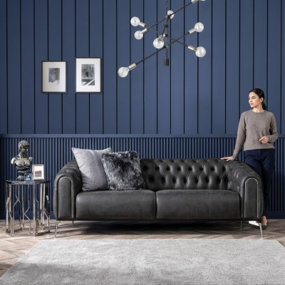 Czarna prosta czteroosobowa sofa w stylu Chesterfield w salonie