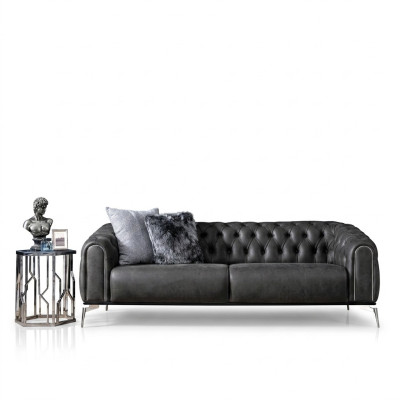 Czarna prosta czteroosobowa sofa w stylu Chesterfield w salonie